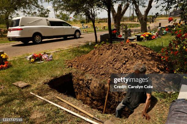 July 20, 2020-A hearse passes as Jesus Torres, age 75, digs a grave after the backhoe broke down at La Piedad cemetery in McAllen. There have been...