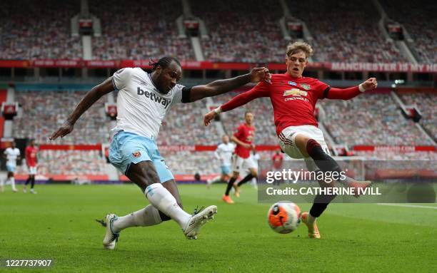 West Ham United's English midfielder Michail Antonio crosses as Manchester United's English defender Brandon Williams tries to defend during the...