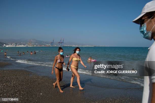 People wearing face masks walk along La Misericordia Beach in Malaga on July 22, 2020. - The world's second-most popular destination after France,...
