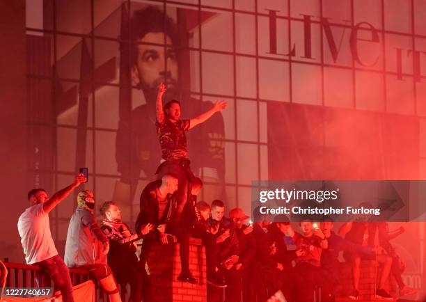 Liverpool fans celebrate outside Anfield stadium in front of an image of Liverpool player Mo Salah during the Premier League match between Liverpool...