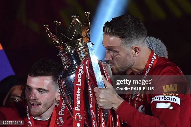 Liverpool's English midfielder Jordan Henderson kisses the Premier League trophy during the presentation following the English Premier League...