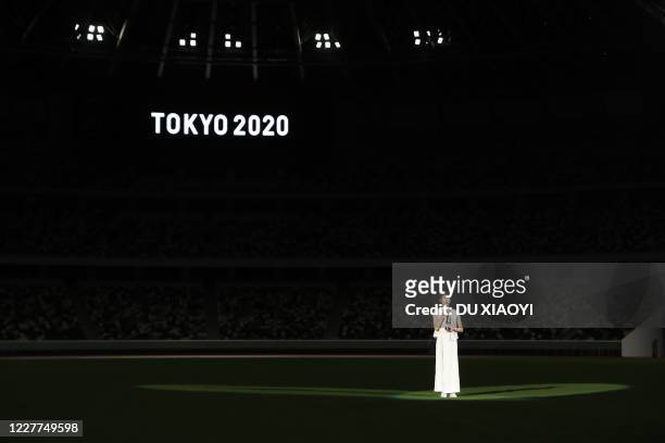 Japanese swimmer Rikako Ikee speaks while holding a lantern containing the Olympic flame during an event to mark one year until the postponed Tokyo...