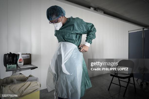 Medical personnel removes protective gear after collecting samples at a COVID-19 free screening booth set up in the arrival hall of the...