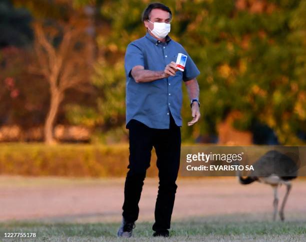 Brazilian President Jair Bolsonaro shows a box of hydroxychloroquine to supporters outside the Alvorada Palace in Brasilia, on July 23, 2020. - In a...