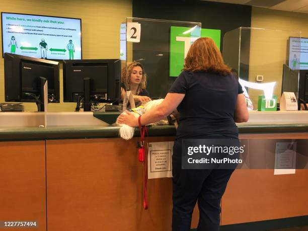 Bank tellers serve customers from behind plexiglass barriers to protect them from the novel coronavirus in Toronto, Ontario, Canada on June 26, 2020.