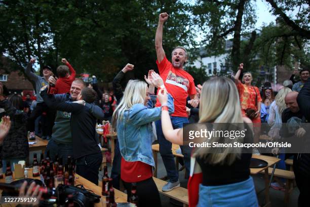 Liverpool fans celebrate in a pub beer garden outside Anfield on July 22, 2020 in Liverpool, England.