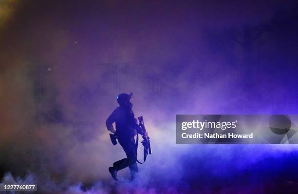 Federal officer runs through tear gas while dispersing a crowd of about a thousand protesters in front of the Mark O. Hatfield U.S. Courthouse on...