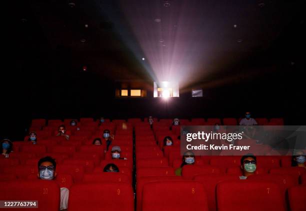 People wear protective masks as they watch a movie in 3D at a theatre on the first day they were permitted to open on July 24, 2020 in Beijing,...