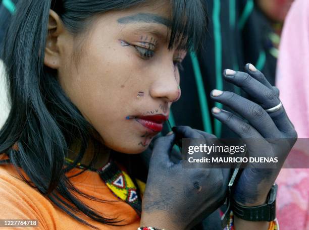 Una joven indígena de la etnia Embera se pinta el rostro con colores rituales antes de iniciar una marcha en Manizales, Colombia el 12 de octubre de...