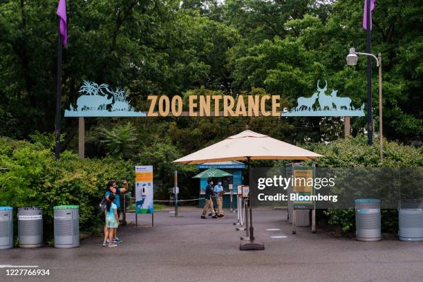 Visitors stand at an entrance to the Bronx Zoo in the Bronx borough of New York, U.S., on Friday, July 24, 2020. On Monday, New York City entered...