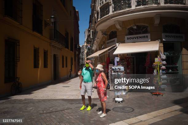 Couple of tourists wearing face masks look out on the street amid coronavirus crisis. Spaniards continue living daily life under a new normality...