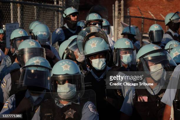 Chicago police look on as Black-led groups lead a rally to defund police, across from the Chicago Police Department's Homan Square facility, on...
