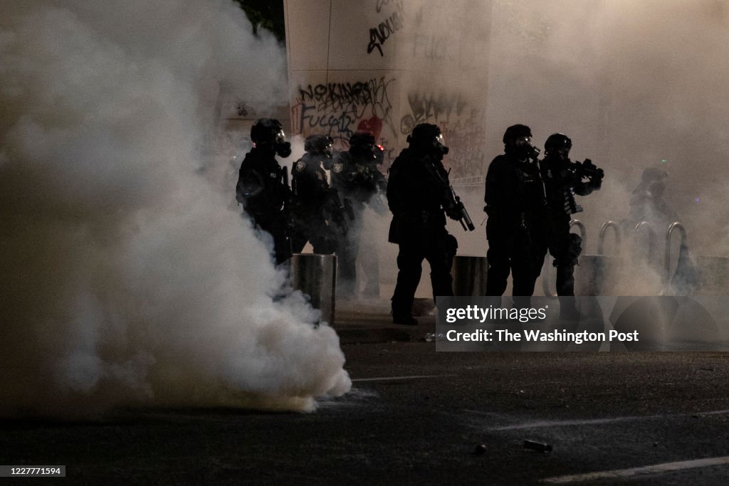 PORTLAND, OR - JULY 21: Federal officers are surrounded by tear