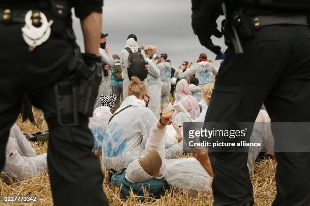 July 2020, North Rhine-Westphalia, Keyenberg: Environmental activists in white overalls are surrounded by the police. About 50 coal opponents had...