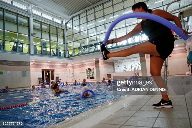 An instructor demonstrates a move during an aqua-fit class in the swimmping pool at Nuffield Health Sunbury Fitness and Wellbeing Gym in...
