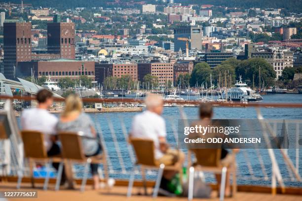 The Oslo town hall is seen as people enjoy the view from a ferry in the Oslo fjord in the Norwegian capital on July 25, 2020 amidst the Covid-19...