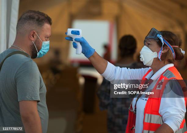 Member of Spanish Red Cross checks the body temperature of an Algerian migrant at Malaga port after being intercepted by Spanish Civil Guards...