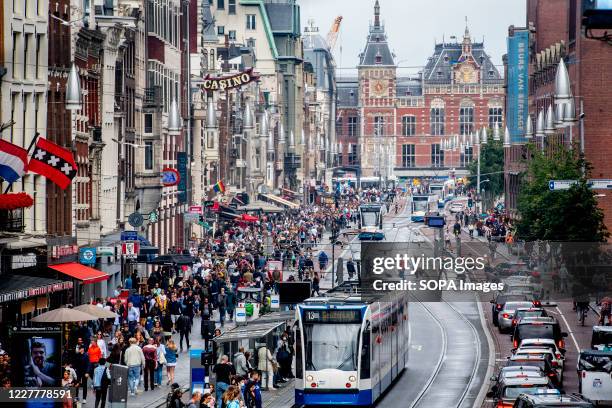 The tram area full with people. Crowded with tourists shopping on the streets and the Dam full of visitors with one-way traffic in the Kalverstraat,...