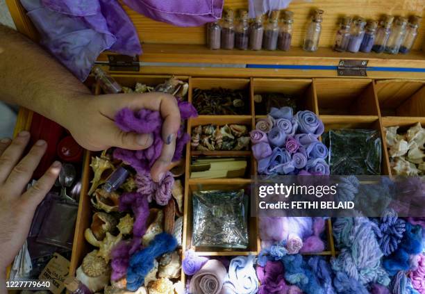 Tunisian craftsman Mohamed Ghassen Nouira displays a box where he keeps samples of yarn and fabric dyed with a purple color he extracted from Murex...