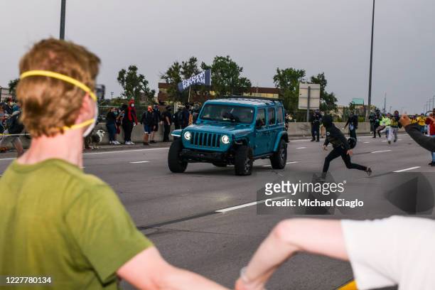 People run to get out of the way as a Jeep speeds through a crowd of people protesting the death of Elijah McClain on I-225 on July 25, 2020 in...