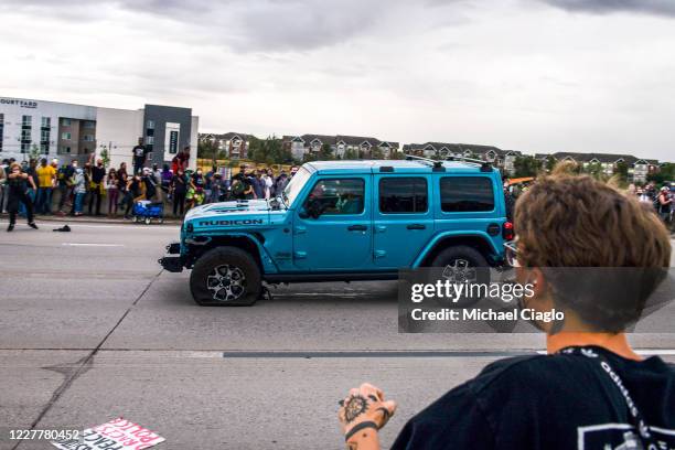 People run to get out of the way as a Jeep speeds through a crowd of people protesting the death of Elijah McClain on I-225 on July 25, 2020 in...