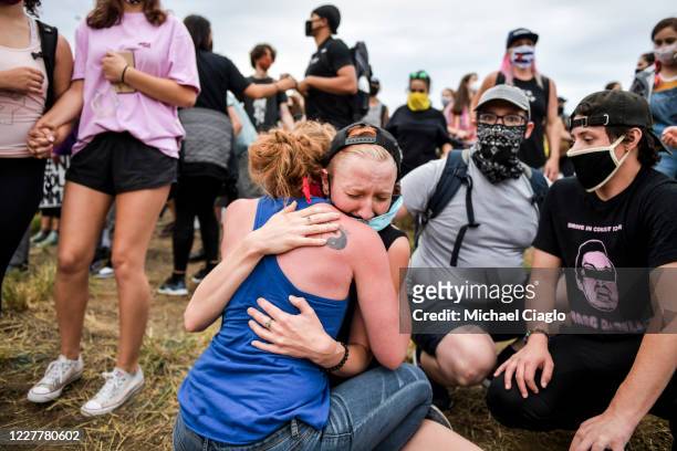 Protesters comfort a woman on the side of the highway after a car sped through the crowd and a man was shot while marching on I-225 to protesting the...