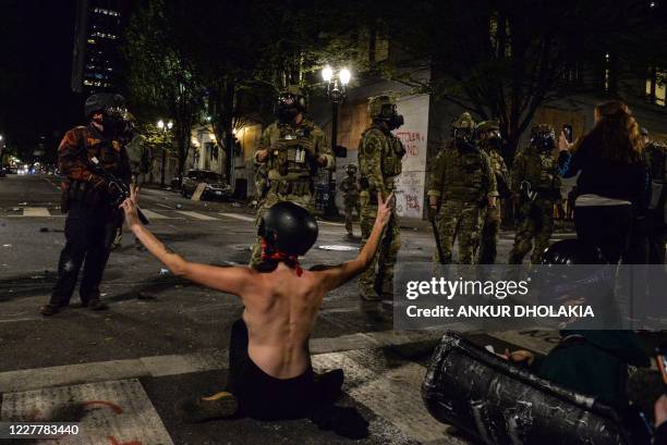 Topless protestor gestures in front of federal police personnel in Portland, Oregon early July 26 as protests continue across the United States...