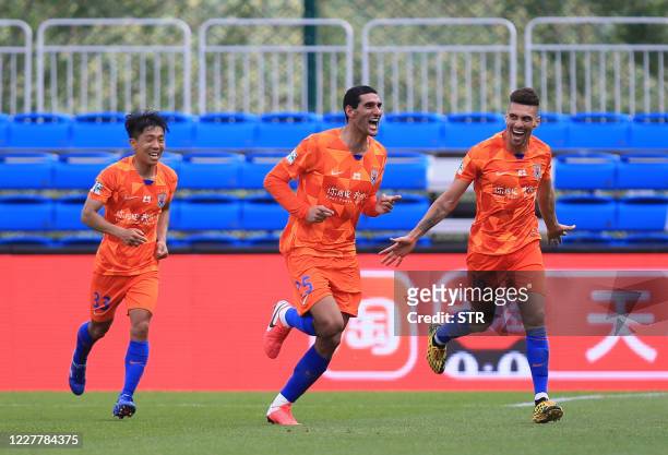 Marouane Fellaini of Shandong Luneng celebrates with teammates Jin Jingdao and Moises after Fellaini scored against Dalian Pro during their Chinese...