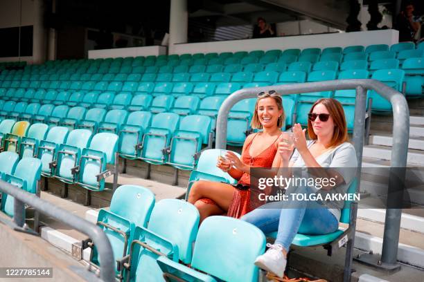 Spectators sit socially distanced leaving spaces between groups as a precaution against the spread of the novel coronavirus as they watch the...