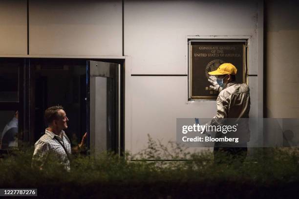 Jim Mullinax, U.S. Consul General in Chengdu, left, speaks with a worker trying to remove a plaque from the front of the U.S. Consulate General...