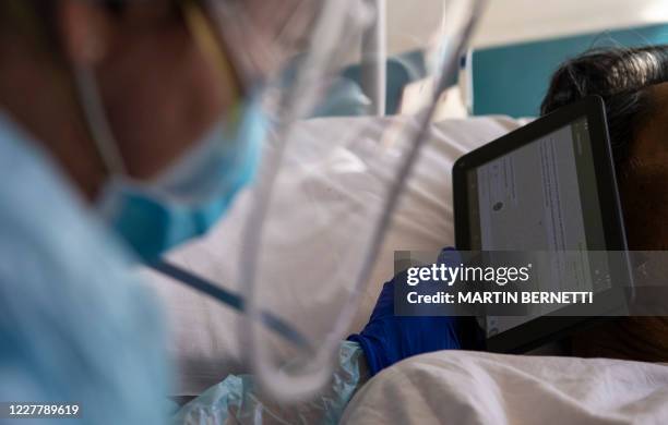 Doctor Moyra Lopez holds an iPad for a terminal patient to listen to a farewell message from his relatives, at the so-called 'humanized farewell'...