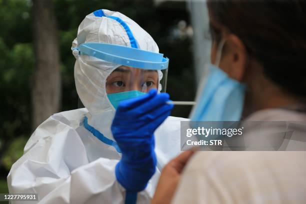 This photo taken on July 26, 2020 shows a health worker carrying out a COVID-19 coronavirus test in Dalian, in China's northeast Liaoning province. -...