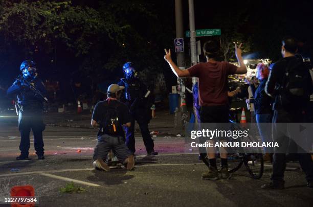 Protestors stand before security officials on a street in Portland, Oregon early July 26 as protests continue across the United States following the...