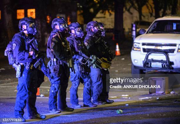 Security officials form a line across a street in Portland, Oregon early July 26 as protests continue across the United States following the death in...