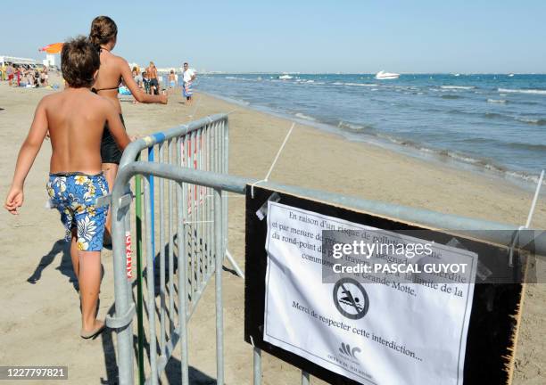 Des personnes se promènent sur une plage située entre la Grande Motte et Carnon, le 06 août 2008, où la baignade a été interdite en raison du rejet...