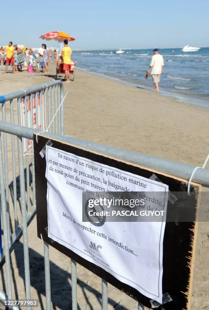 Des personnes se promènent sur une plage située entre la Grande Motte et Carnon, le 06 août 2008, où la baignade a été interdite en raison du rejet...