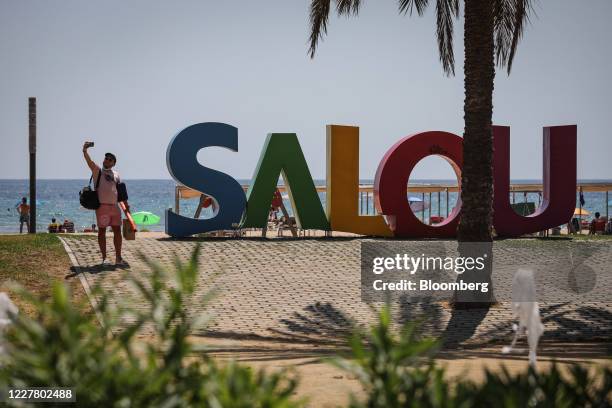 Visitor takes a 'selfie' photograph in front of a tourist sign in Salou, Spain, on Monday, July 27, 2020. Spain's tourism industry is at increasing...