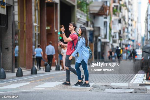 tourists exploring downtown buenos aires with smart phone - couple crossing street stock pictures, royalty-free photos & images