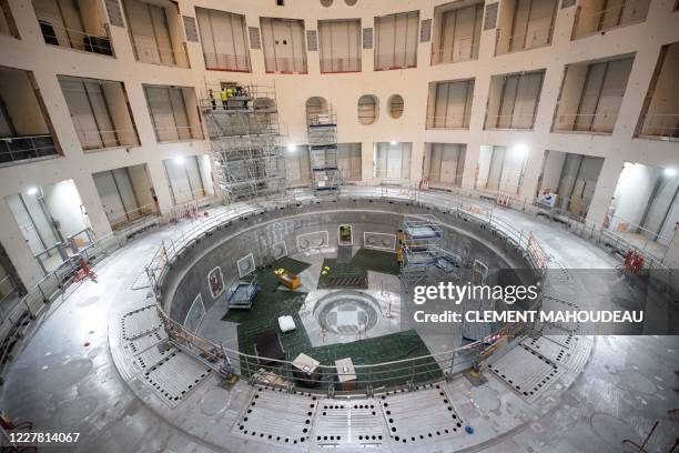 Technicians work on the bioshield inside the Tokamak Building with the base of the cryostat at its base during the launch of the assembly stage of...