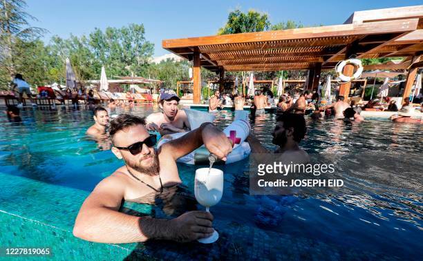 Lebanese people enjoy a sunny day in a swimming pool in the upmarket Faqra Club in the Lebanese mountains north of Beirut on July 25, 2020. - Panama...