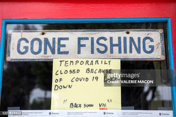 Sign reading "Gone Fishing" is pictured on the window of a closed barber shop in Santa Monica, California, on July 28 amid the coronavirus pandemic.