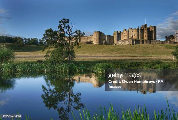 Alnwick Castle, home to the Duke and Duchess of Northumberland, reflected in the River Aln.