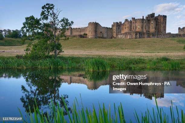 Alnwick Castle, home to the Duke and Duchess of Northumberland, reflected in the River Aln.