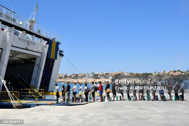 Migrants escorted by Guardia Di finanza police queue to board on a tourists ferry boat to Porto Empedocle in the Italian Pelagie Island of Lampedusa...
