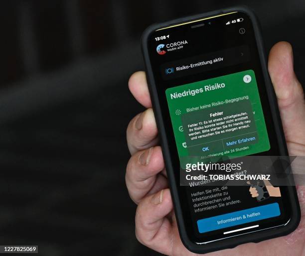 Man holds a smartphone displaying an error message of Germany's CORONA warn-app contact tracing app for the novel coronavirus in Berlin on July 29,...