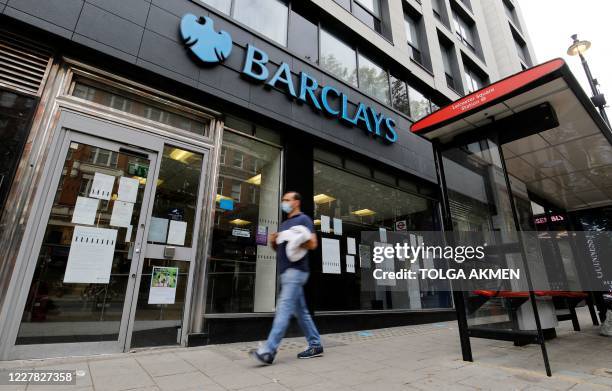 Pedestrian wearing a face mask or covering due to the COVID-19 pandemic, walks past a branch of a Barclays bank in central London on July 29, 2020. -...