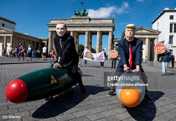 Two activists disguised as US President Trump and Russian President Putin ride two models of nuclear bombs in front of the Brandenburg Gate during a...