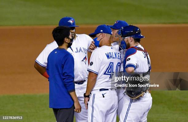 Toronto Blue Jays pitcher Shun Yamaguchi s American to Japanese translator facilitates the conference on the mound with pitching coach Pete Walker...