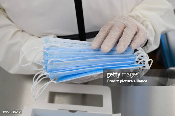 July 2020, Saxony, Ohorn: An employee of PHB Pulsnitzer Hygiene Berufsbekleidung GmbH sorts disposable masks in production. The company from Eastern...