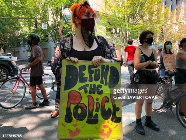 Woman holds a "Defund the Police" sign in Portland, Oregon on July 30, 2020. - Police in Portland cleared parks and nearby roads in the downtown area...